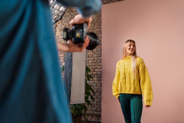 A young photographer taking picures of model, backstage of photoshooting in studio.