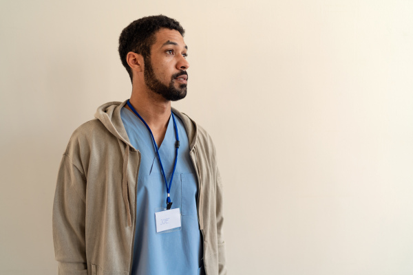 A depressed young male doctor or caregiver over beige background.