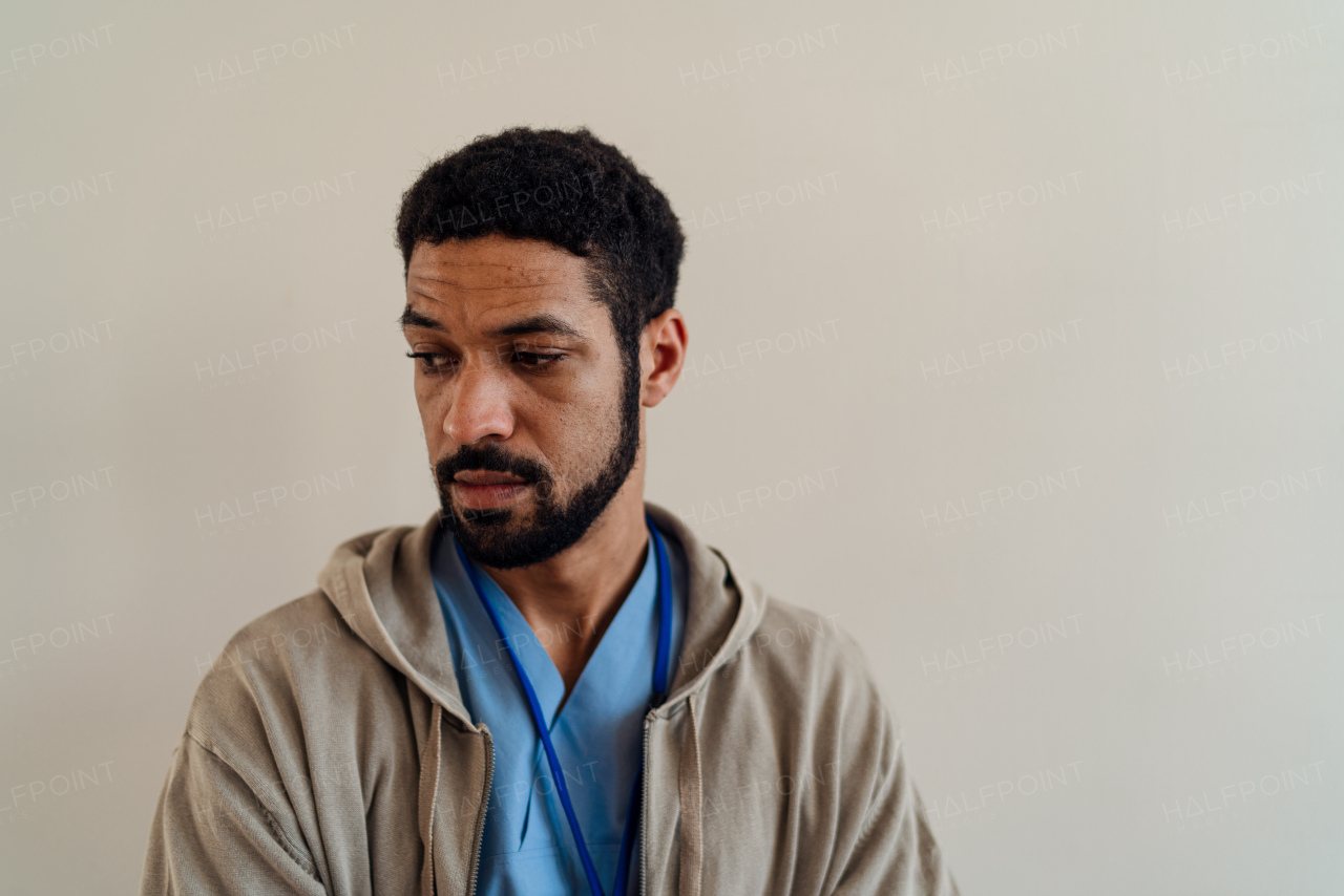 A depressed young male doctor or caregiver over beige background.