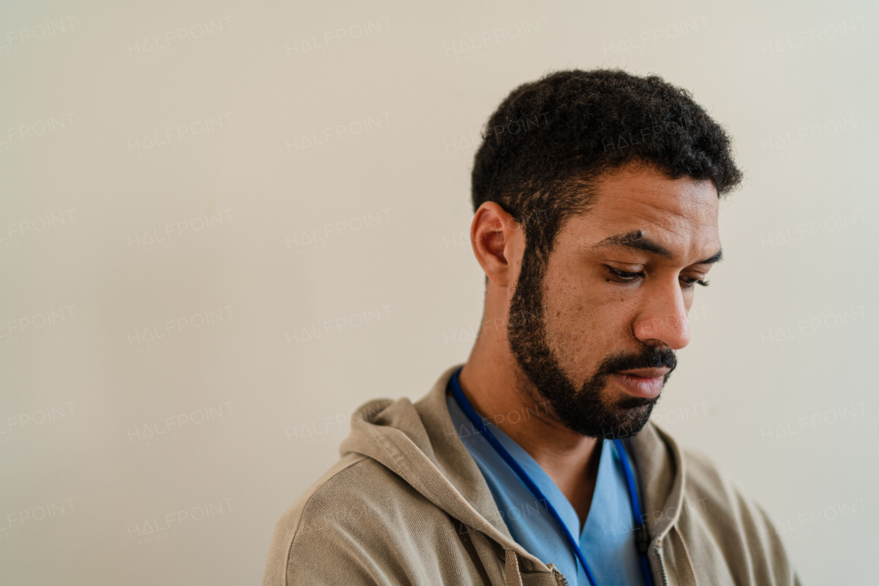 A depressed young male doctor or caregiver over beige background.