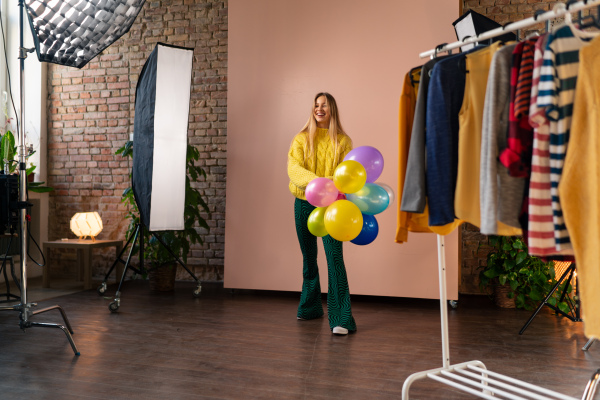 A studio portrait of a happy young blonde woman with balloon over pink background.