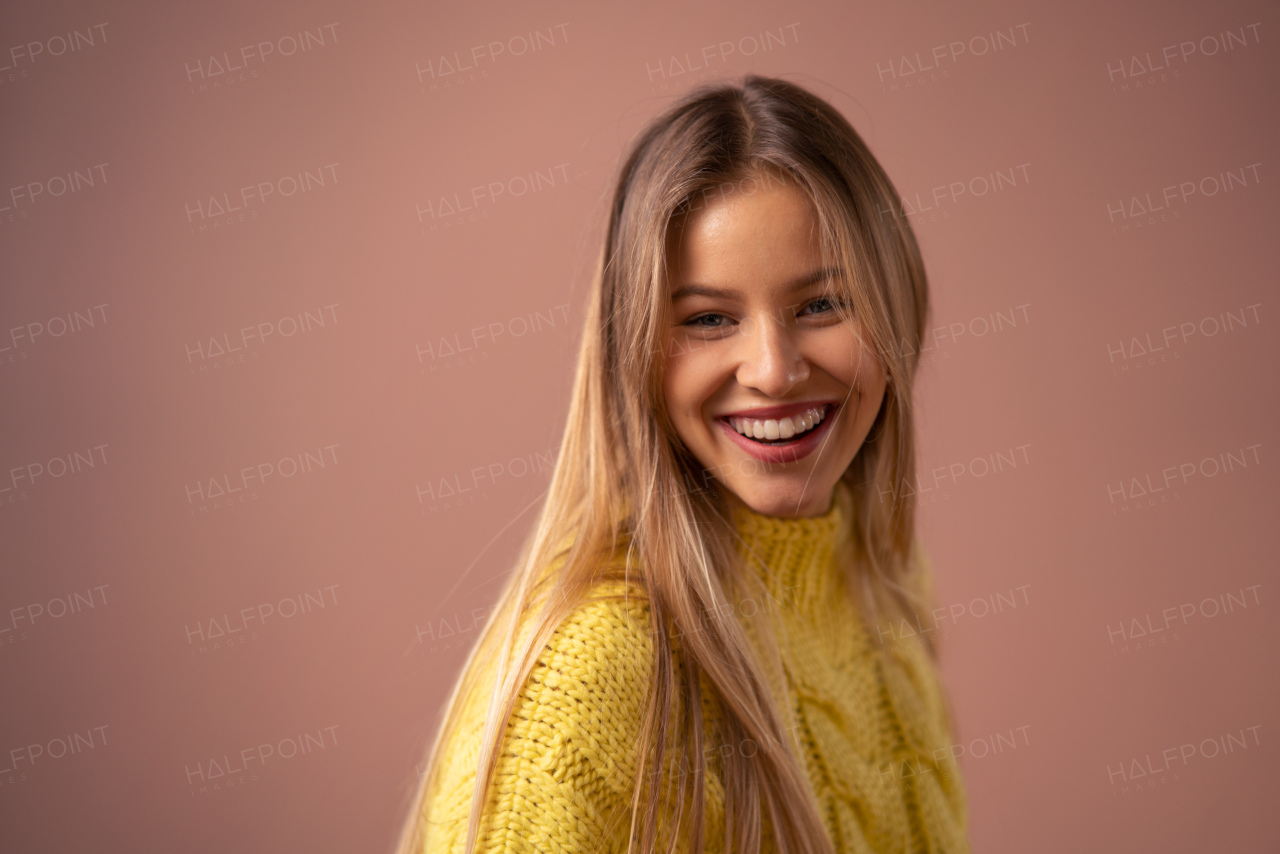 Fashion studio portrait of a young blonde woman posing over pink background.