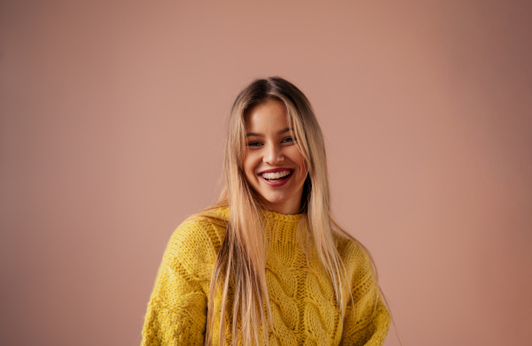 Fashion studio portrait of a young blonde woman posing over pink background.