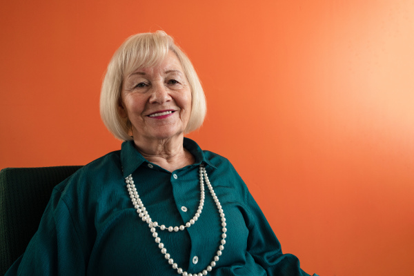 A smiling elegant elderly woman sitting in armchair