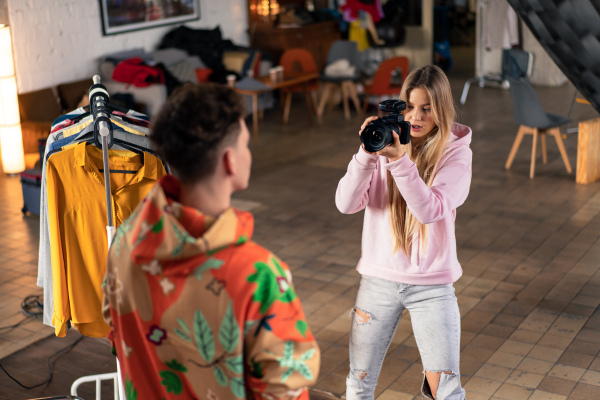 A young photographer taking picures of model, backstage of photoshooting in studio.