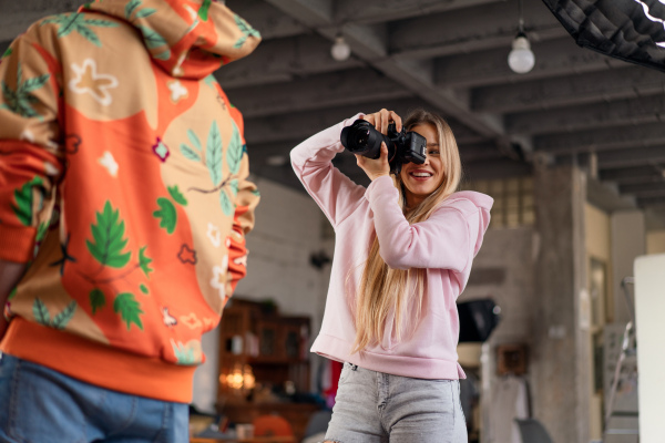 A young photographer taking picures of model, backstage of photoshooting in studio.