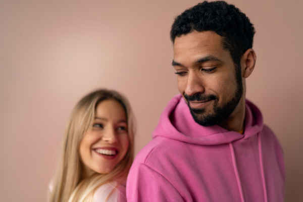 A fashion studio portrait of a happy young blonde woman in hoodie posing over pink background.