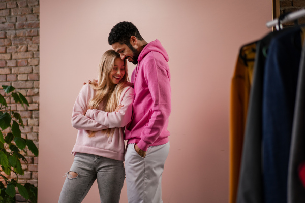 A fashion studio portrait of a happy young blonde woman in hoodie posing over pink background.