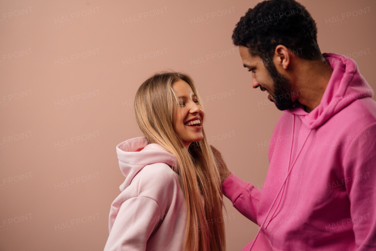 A fashion studio portrait of a happy young blonde woman in hoodie posing over pink background.