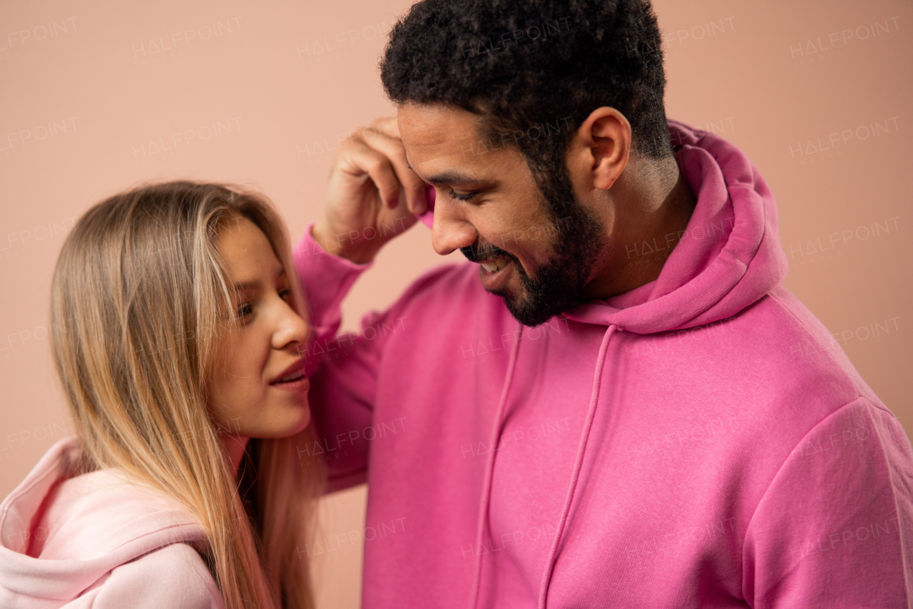 A fashion studio portrait of a happy young blonde woman in hoodie posing over pink background.