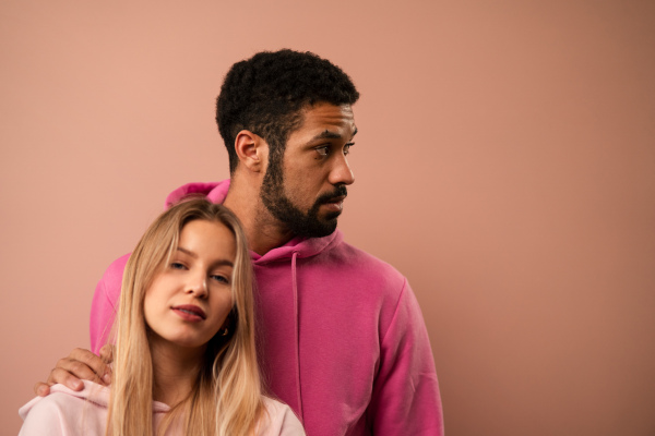 A fashion studio portrait of a happy young blonde woman in hoodie posing over pink background.