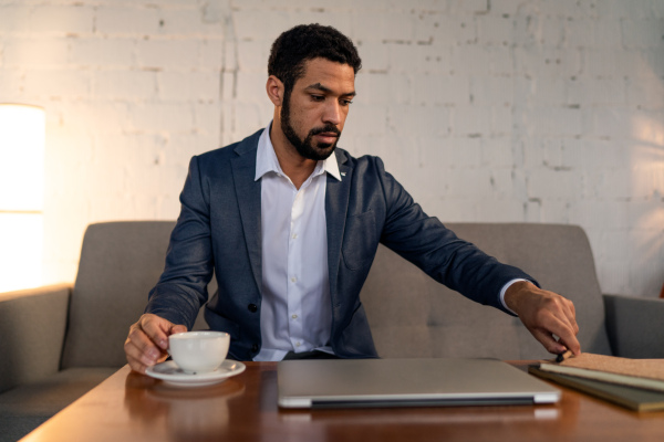 A busy young businessman having coffee and doing his work.