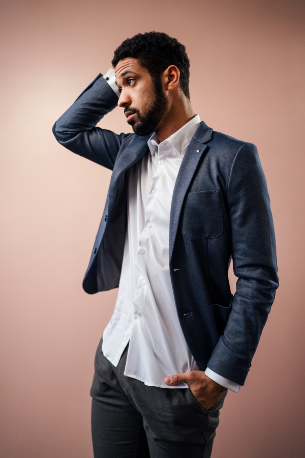 A serious young businessman posing in studio over beige background.