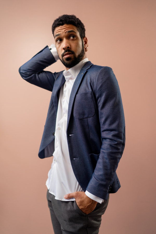 A serious young businessman looking at camera, studio shot.