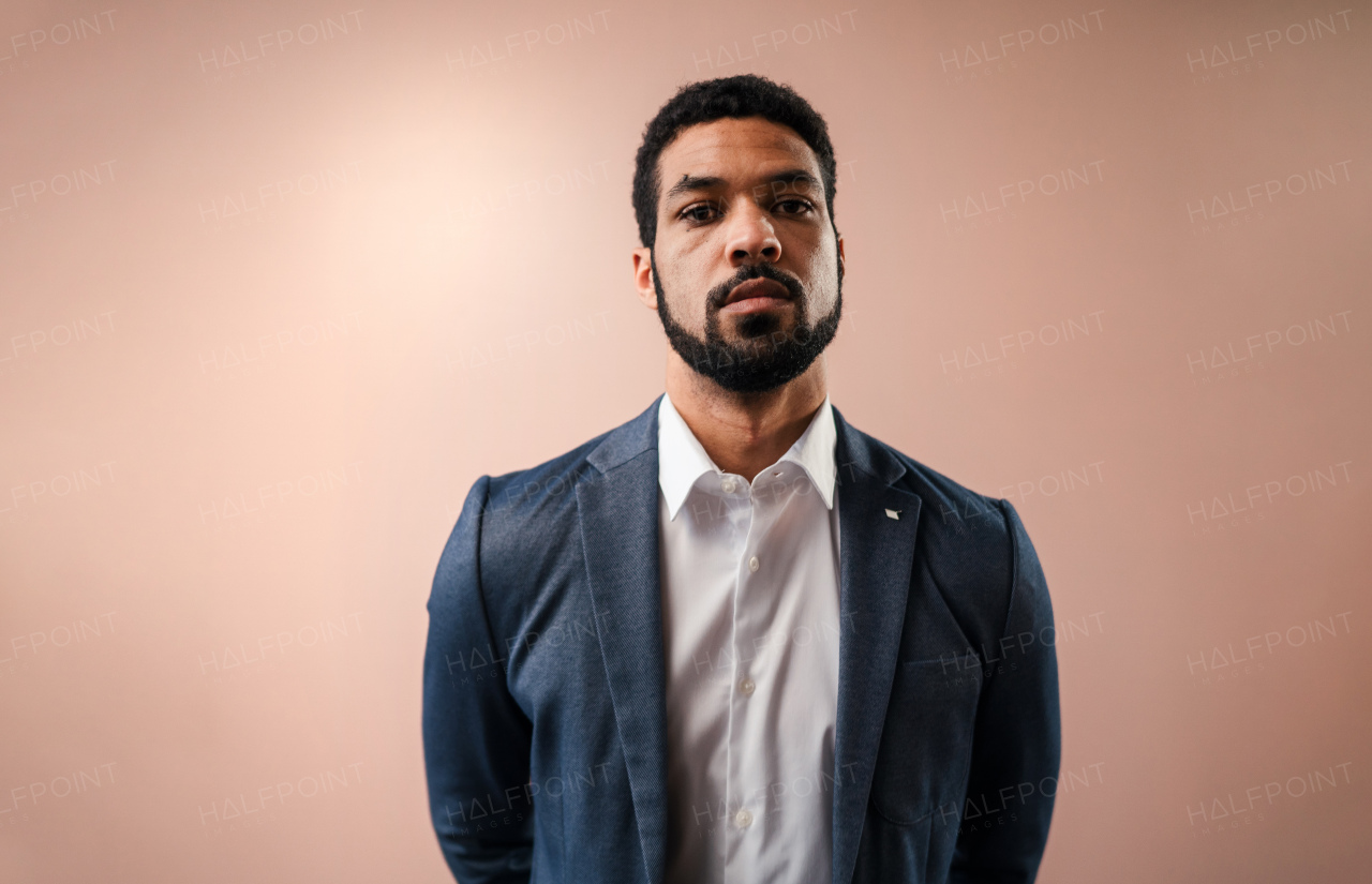 A serious young businessman looking at camera, studio shot.