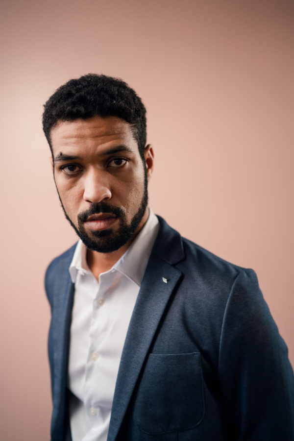 A serious young businessman looking at camera, studio shot.