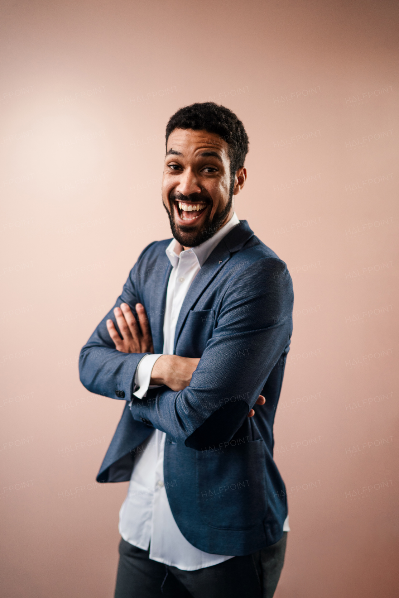 A happy young succeeful businessman smiling with arms crossed, studio shot.