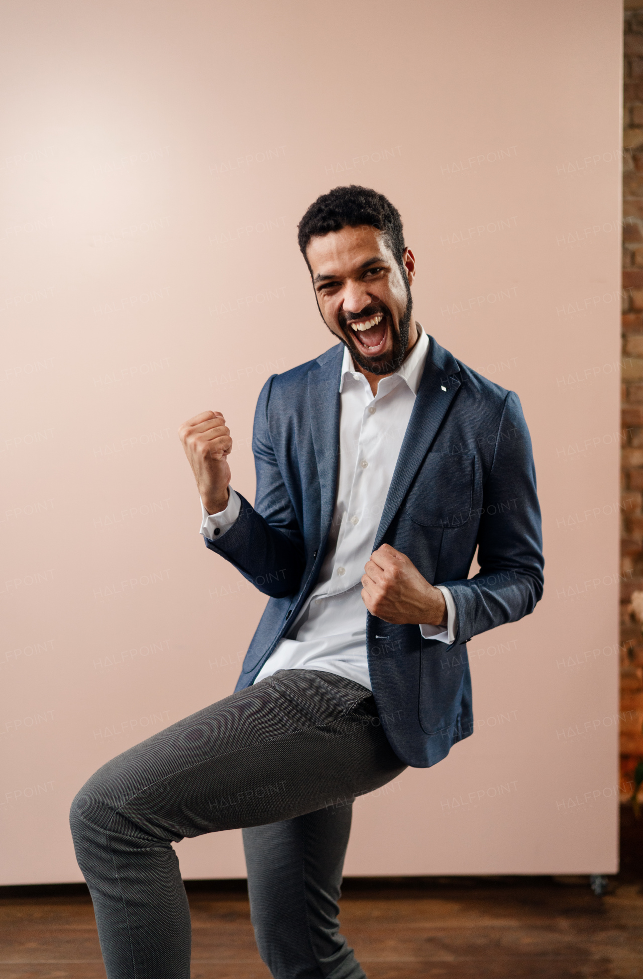 A happy young succeeful businessman yes gesturing and showing fist, studio shot.