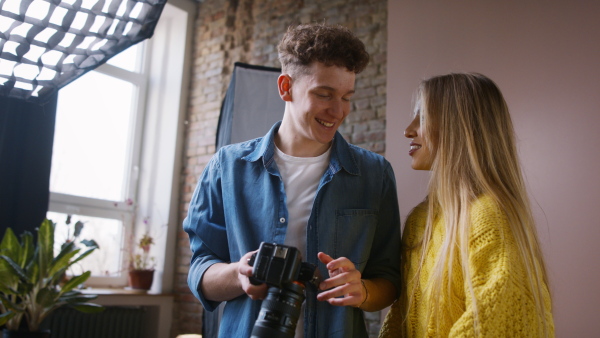 A young photographer showing picures to model, backstage of photoshooting in studio.