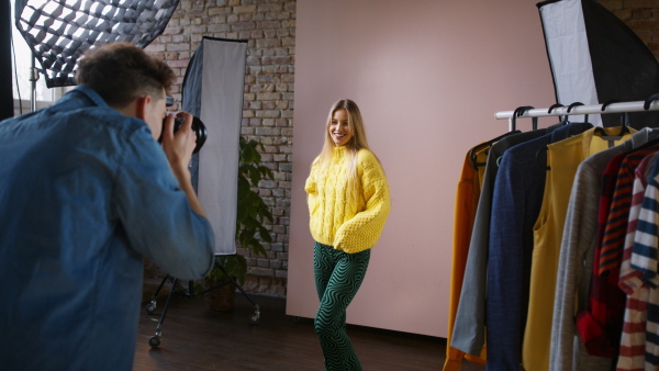 A young photographer taking picures of model, backstage of photoshooting in studio.