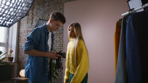 A young photographer showing picures to model, backstage of photoshooting in studio.