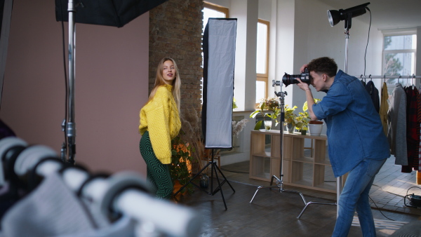 A young photographer taking picures of model, backstage of photoshooting in studio.