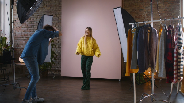 A young photographer taking picures of model, backstage of photoshooting in studio.