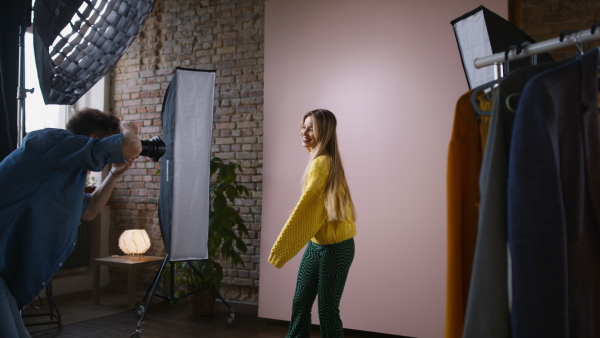 A young photographer taking picures of model, backstage of photoshooting in studio.