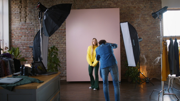 A young photographer taking picures of model, backstage of photoshooting in studio.