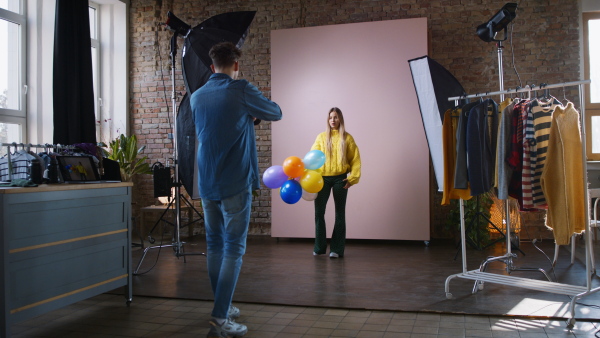 A young photographer taking picures of model, backstage of photoshooting in studio.