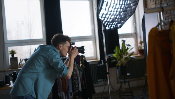 A young photographer taking picures of model, backstage of photoshooting in studio.