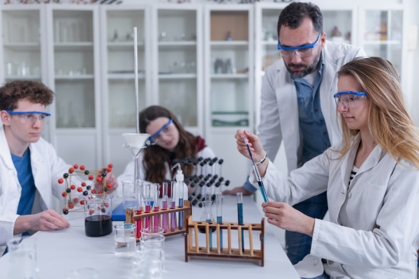 Science students with a teacher doing chemical reaction experiment in the laboratory at university.