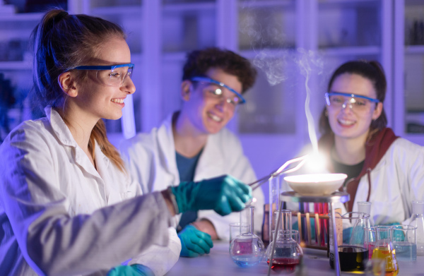 Excited science students doing a chemical experiment in the laboratory at university.