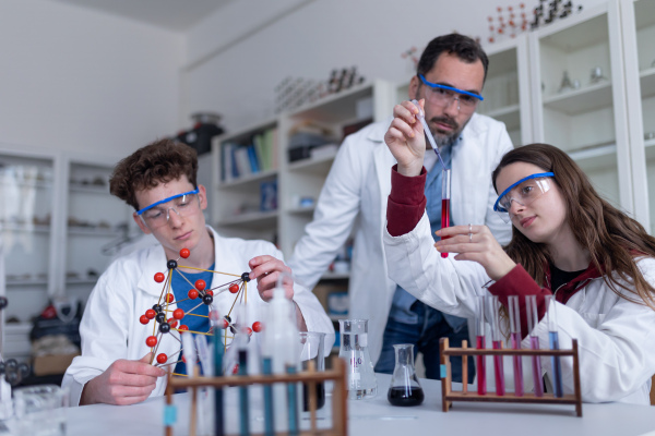 Science students with a teacher doing chemical reaction experiment in the laboratory at university.