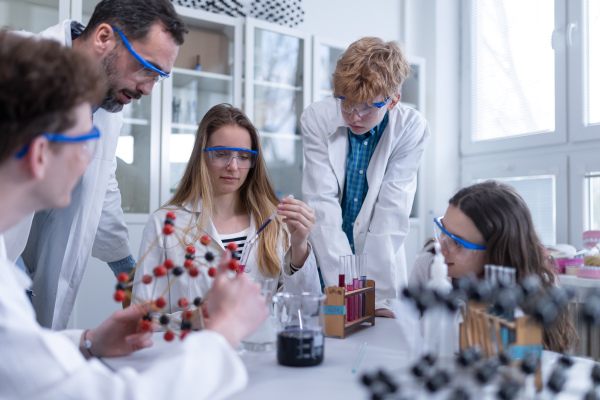 Science students with a teacher doing chemical reaction experiment in the laboratory at university.