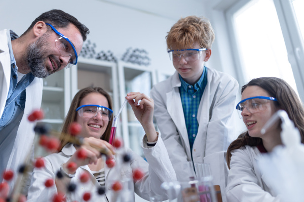 Science students with a teacher doing chemical reaction experiment in the laboratory at university. Low angle view.