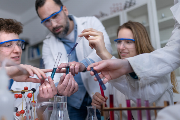 Science students with a teacher doing chemical reaction experiment in the laboratory at university.