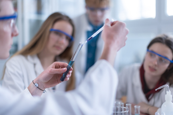 Science students doing a chemical experiment in the laboratory at university. Close-up.