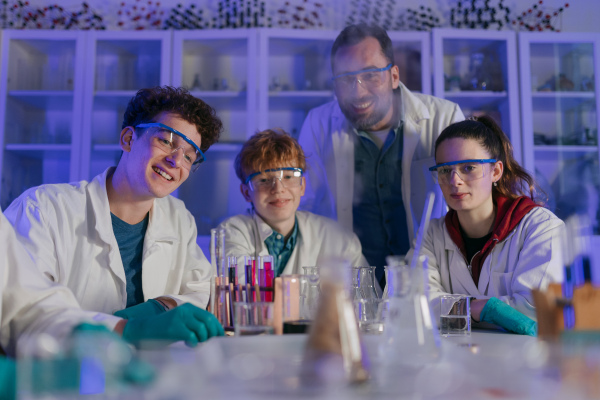 Science students with a teacher doing chemical reaction experiment in the laboratory at university.