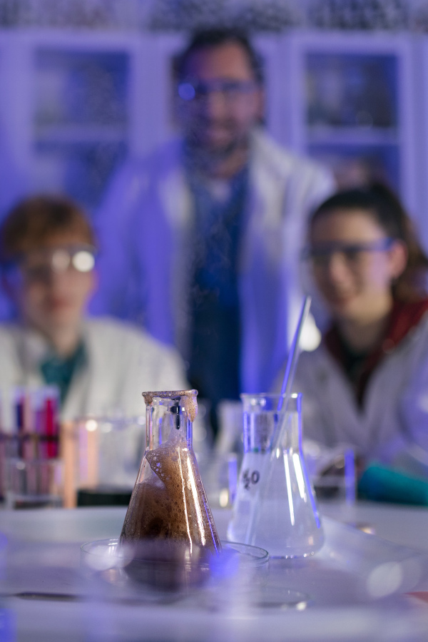 Science students with a teacher doing chemical reaction experiment in the laboratory at university.