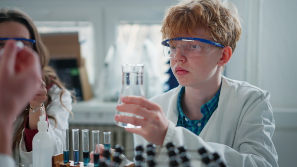 Science students doing chemical experiment in laboratory at university, close-up.