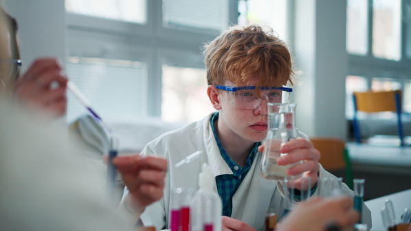 Science students doing chemical experiment in laboratory at university, close-up.