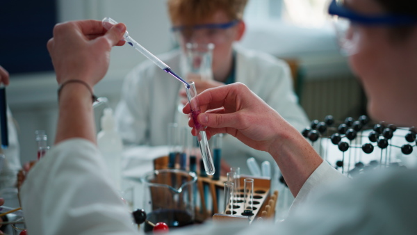 Science students doing chemical experiment in laboratory at university, close-up.