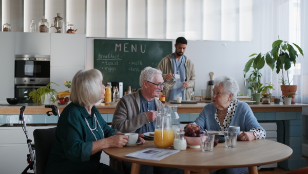 A group of cheerful seniors enjoying breakfast in nursing home care center.