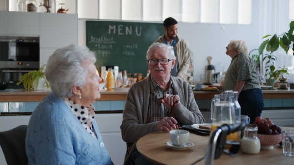 A smiling elderly woman and man enjoying breakfast in nursing home care center.