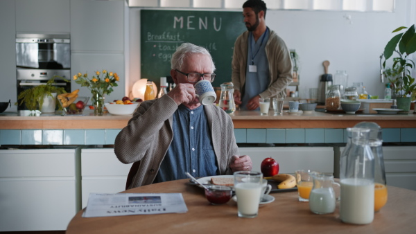 A smiling elderly man enjoying breakfast in nursing home care center.