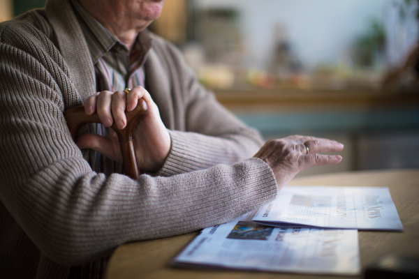 A close-up of elderly man reading newspaper in nursing home care center.