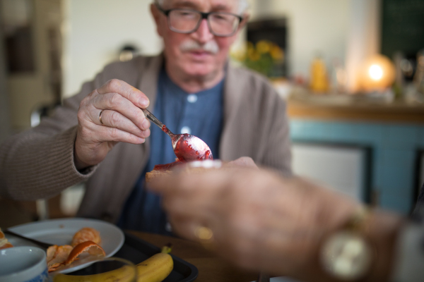 A close-up of senior man enjoying breakfast in nursing home care center.