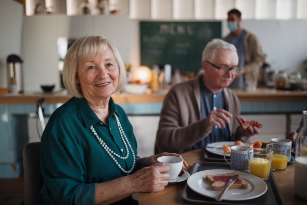 A smiling elderly woman and man enjoying breakfast in nursing home care center.