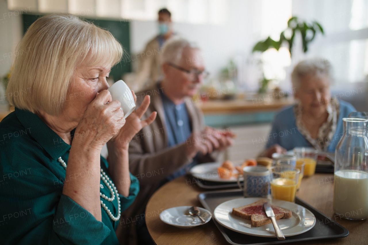 A group of cheerful seniors enjoying breakfast in nursing home care center.